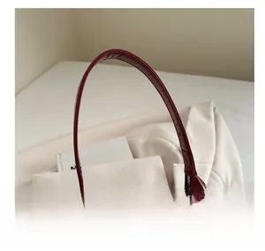 Détail de la poignée en cuir verni bordeaux et de la fermeture éclair en métal du sac