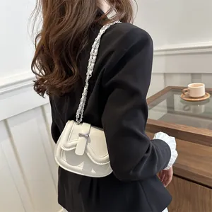 Minimalist cream saddle bag with wavy stitching and chain strap on a business outfit