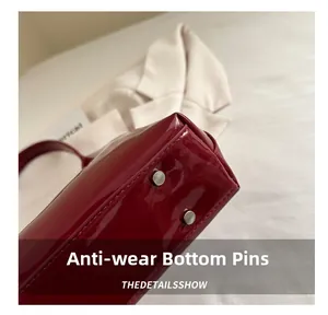 Gros plan du fond du sac en cuir verni rouge avec des clous de protection argentés