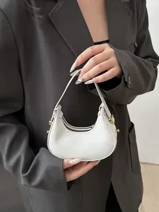 Detailed macro view of white lychee textured leather mini crescent handbag with gold hardware