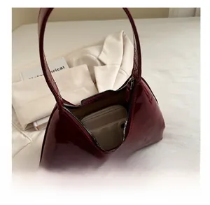 Capacité intérieure du sac en cuir verni bordeaux montrant le rangement du téléphone