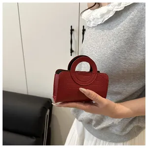 Détail d'un sac à main rouge en similicuir croco avec une poignée circulaire unique