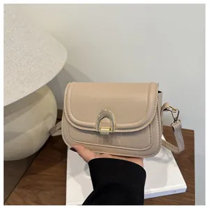 Detail der beigen Satteltasche mit U-förmiger Goldschnalle und glatter Lederstruktur