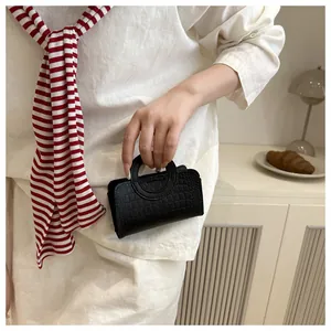 Gros plan d'un mini sac à main noir à motif crocodile avec une poignée anneau ronde