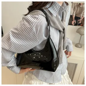 Sac hobo en cuir verni noir brillant avec logo embossé porté à l'épaule