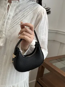 Close-up of black lychee leather crescent bag with gold zipper and metal buckles