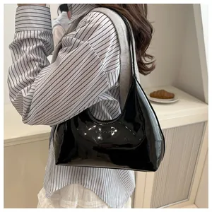 Détail d'un sac à bandoulière en cuir verni brillant avec logo gaufré sur un mannequin
