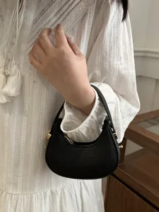 Detail of black litchi grain mini hobo bag with gold hardware and smooth zipper