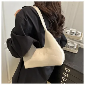 Détail du sac hobo en cuir verni crème avec logo embossé porté à l'épaule