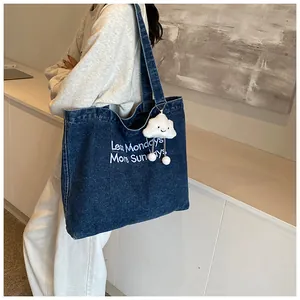 Detail of dark blue denim tote bag with Less Mondays embroidery and cloud charm