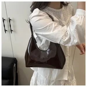 Détail du sac sous le bras en cuir verni marron foncé brillant avec logo et zip