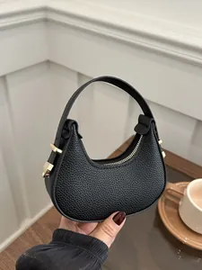 Detailed close-up of a mini black lychee pattern crescent bag with premium gold hardware