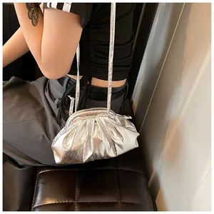 Detailed view of silver pleated shell bag with metallic texture and slender shoulder strap