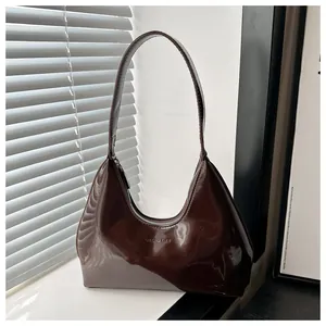 Détail du sac hobo en cuir verni marron foncé brillant avec le logo de la marque GALOAD CULT