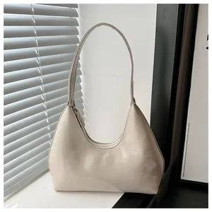 Détail du sac hobo en cuir verni crème brillant avec fermeture éclair et logo de la marque