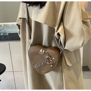 Vue détaillée d'un sac en cuir marron en forme de cœur avec rivets et boucle métal