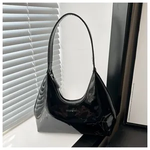 Détail du sac hobo en cuir verni noir brillant avec logo de la marque en lettres argentées