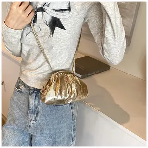 Detail of a metallic gold pleated crossbody bag showing soft texture and fine shoulder strap