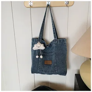 Detailed texture of blue denim tote bag with leather logo and plush cloud charm