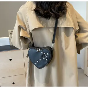 Détail d'un sac à bandoulière en cuir PU noir en forme de cœur avec clous punk argentés et boucle