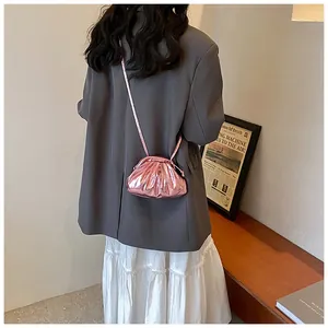 Détail du sac plissé rose métallisé porté avec un blazer gris et une robe blanche