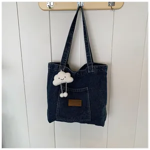Detail of blue denim tote bag with a leather label and a cute cloud plush charm