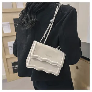Détail du sac bandoulière gris clair avec rabat ondulé et bandoulière chaîne argentée