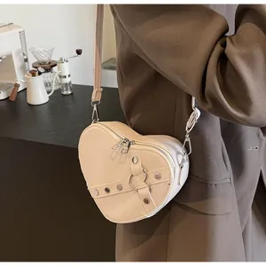 Détail du sac à main cœur crème avec des rivets métalliques et double fermeture éclair