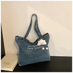 Detail of blue denim tote bag with Less Mondays More Sundays embroidery and cloud charm