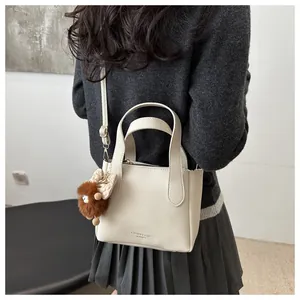 Detail of off-white lychee pattern leather bucket bag with cute plush ball charm