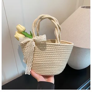 Détail du cabas en paille tressée avec nœud en dentelle blanche et anses en corde