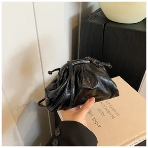 Close-up of black glossy leather dumpling bag with pleated texture and drawstring