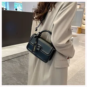 Side view of a black chic crossbody bag with metal lock and fashion brand tag