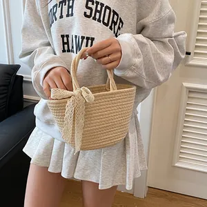 Sac fourre-tout tissé crème avec nœud en dentelle blanche porté par un mannequin