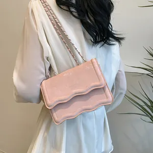 Sac à bandoulière rose chic avec rabat ondulé et chaîne, porté par un mannequin