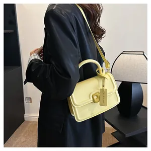 Detail of yellow crossbody bag with unique buckle and fashion tag on black jacket