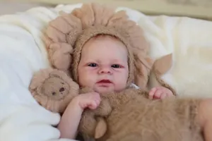 Close-up of Elijah reborn doll wearing a handmade beige lion knit outfit and hat