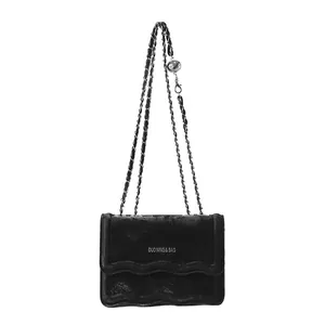 Sac bandoulière minimaliste en velours noir avec bord ondulé et chaîne en métal
