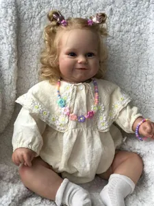Détail de la poupée reborn Maddie 60cm avec boucles blondes et broderie de marguerites
