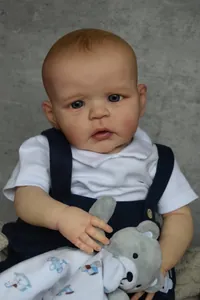 Close-up of Sandie doll with realistic skin texture, blue eyes and plush bear security blanket