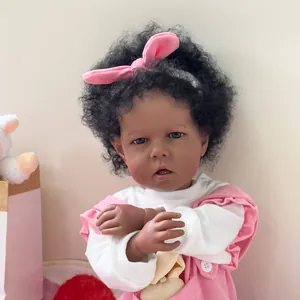 Muñeca Reborn Liam de 50cm con piel oscura, pelo negro rizado, ojos azules y peto rosa