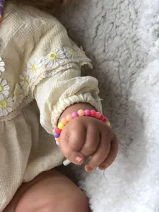 Gros plan d'un bracelet en perles colorées sur le poignet d'un bébé avec dentelle soleil