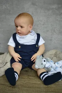 Detailed close-up of a 60cm lifelike reborn doll wearing a navy romper and striped socks