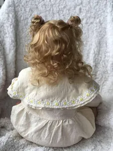 Détail de robe de bébé jaune clair avec broderie marguerite et col en dentelle blanche