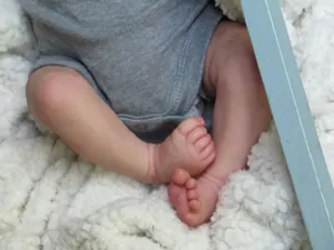 Realistic reborn baby doll Levi with 3D painted skin wearing a grey cotton bodysuit