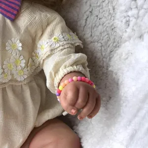Poupée Maddie reborn avec bracelet en perles macaron colorées sur couverture en peluche