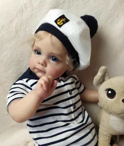 Detail of reborn toddler Maggi boy doll in navy outfit with lifelike blue eyes and golden curls
