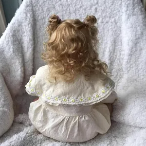 Vue arrière de la poupée Reborn Maddie 60cm avec boucles blondes et robe en dentelle marguerite
