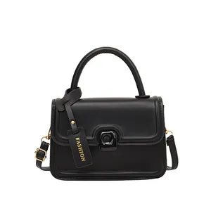 Classic black leather handbag with adjustable strap and golden buckle on white background