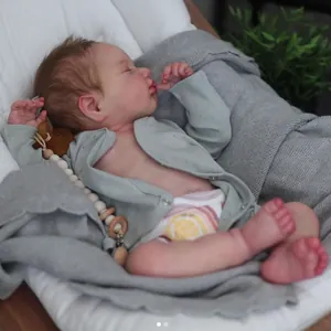 Detail van slapende Reborn babypop met lichtblauw gebreid vest en een bedrukte luier om
